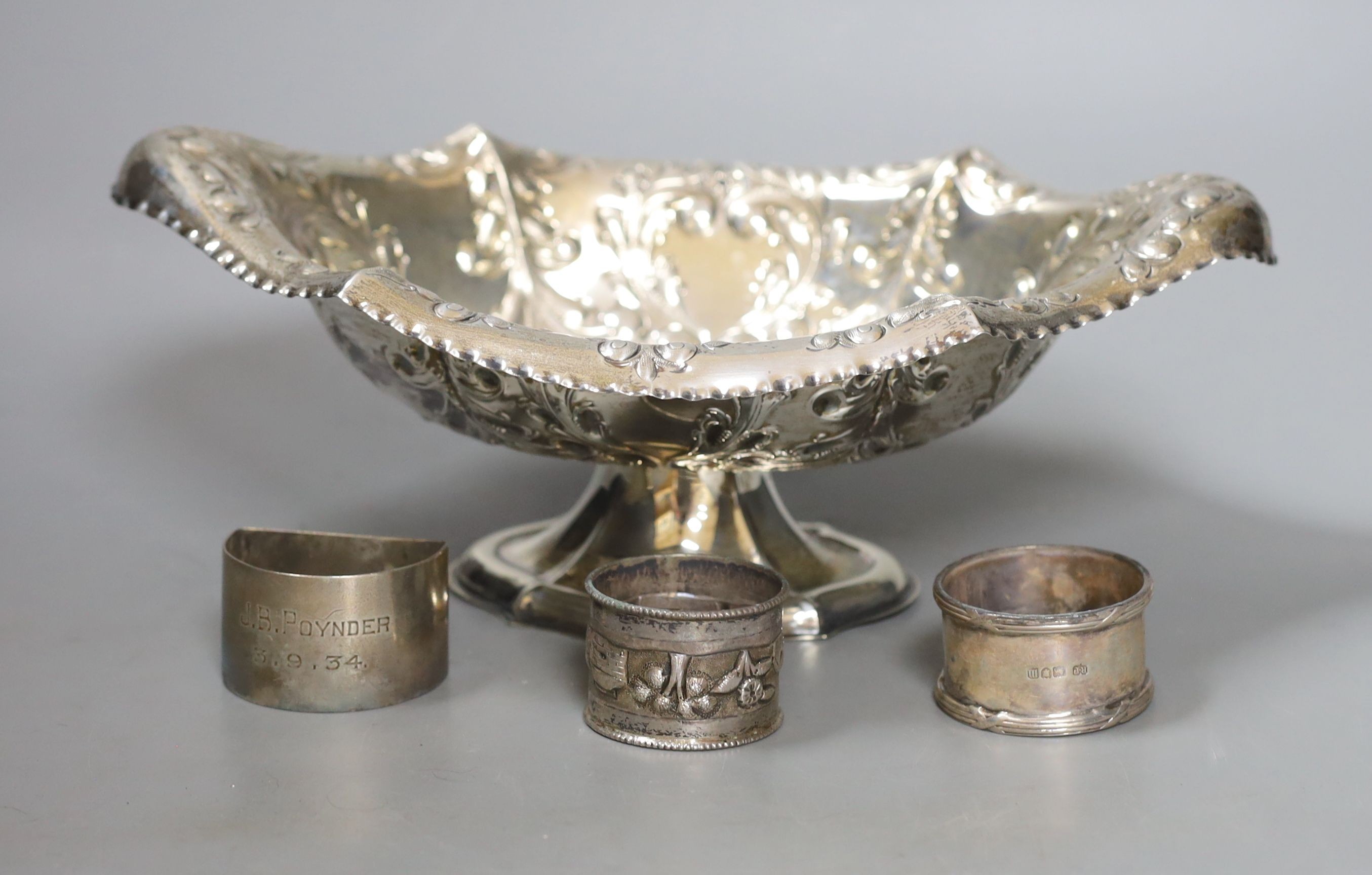 An Edwardian repousse silver pedestal bowl, Sheffield, 1901, 28.5cm and three silver napkin rings, 12.5oz.